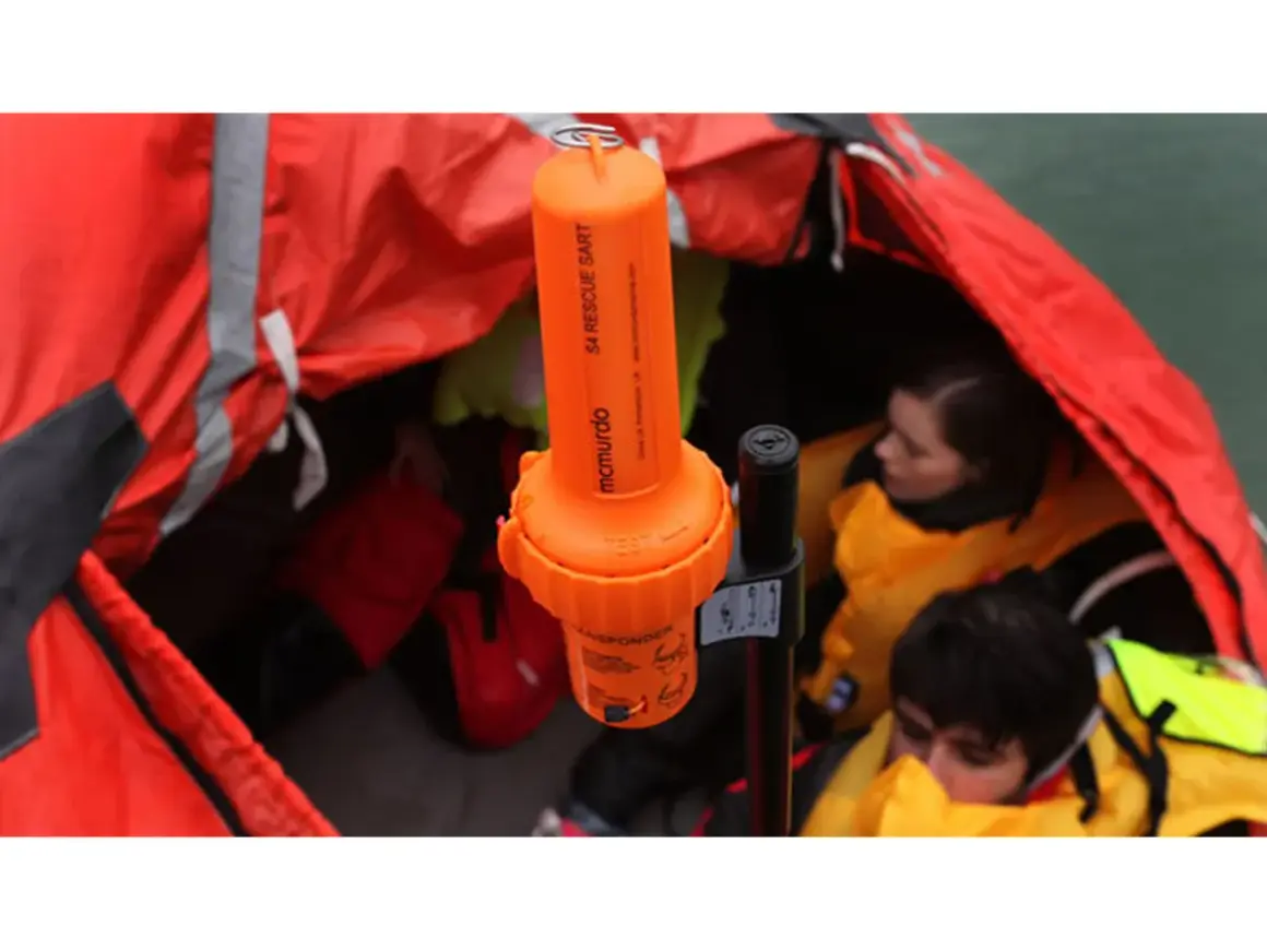 Arancione transponder navi SART McMurdo in una zattera di salvataggio con persone con giubbotti di salvataggio.