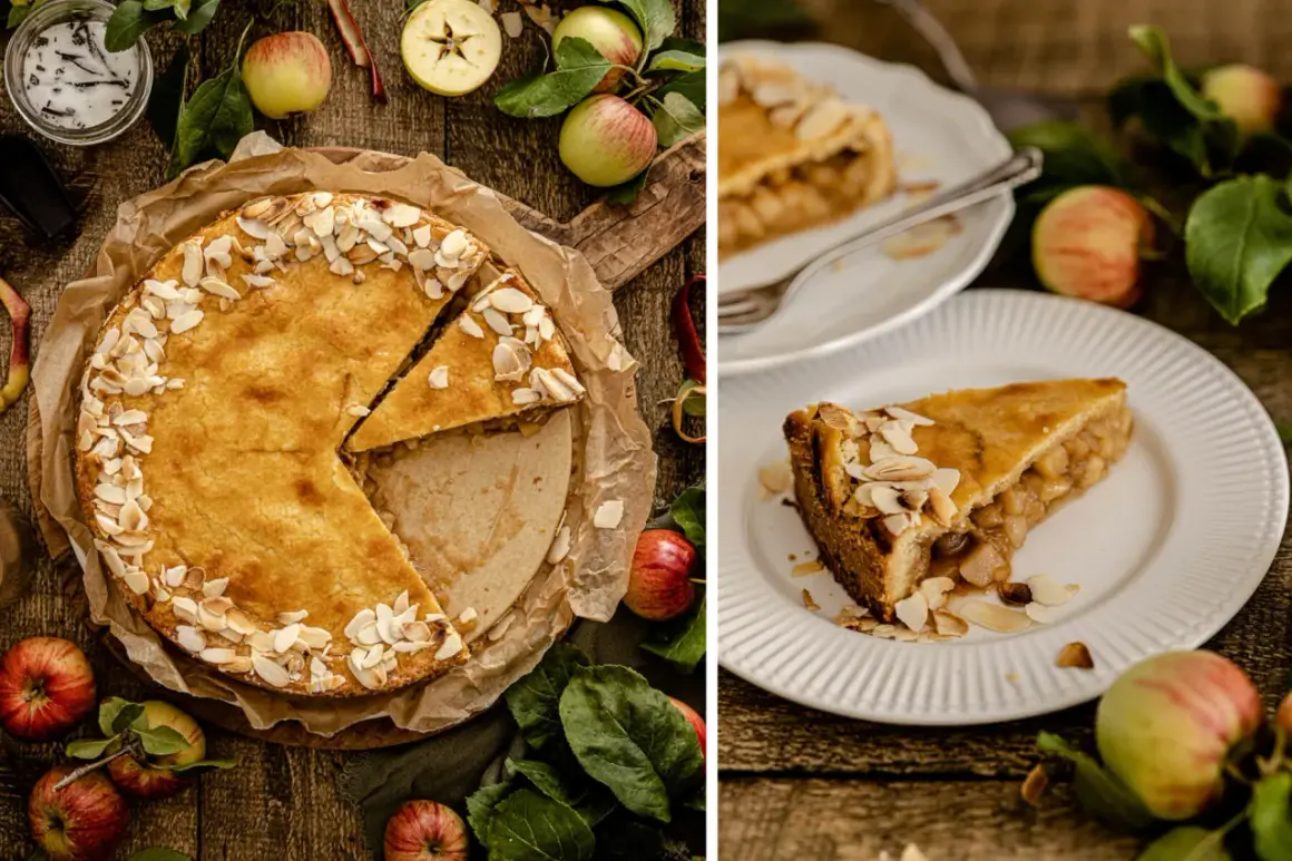 Ein goldbrauner gedeckter Apfelkuchen, bestreut mit Mandelblättchen, wird auf einem Holztisch präsentiert. Daneben liegen frische Äpfel und Blätter.