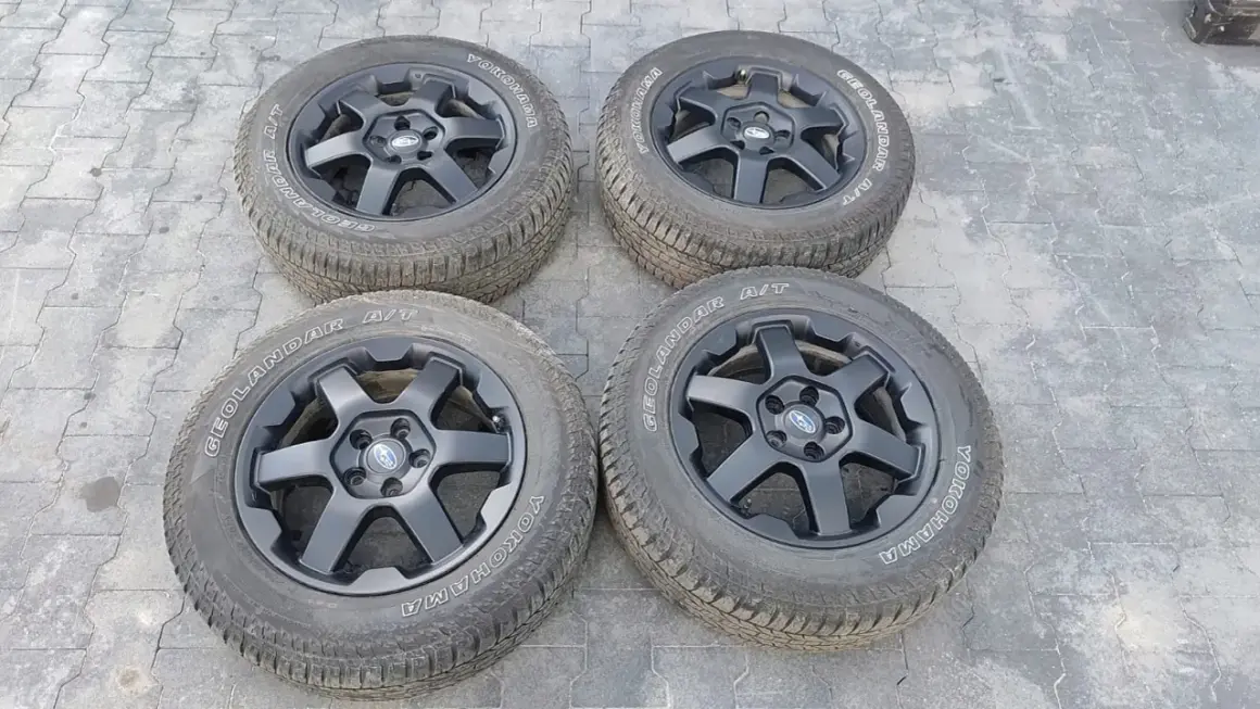 Cztery czarne felgi z oponami Yokohama Geolandar A/T, idealne do Subaru Outback Wilderness, gotowe na każdą przygodę.