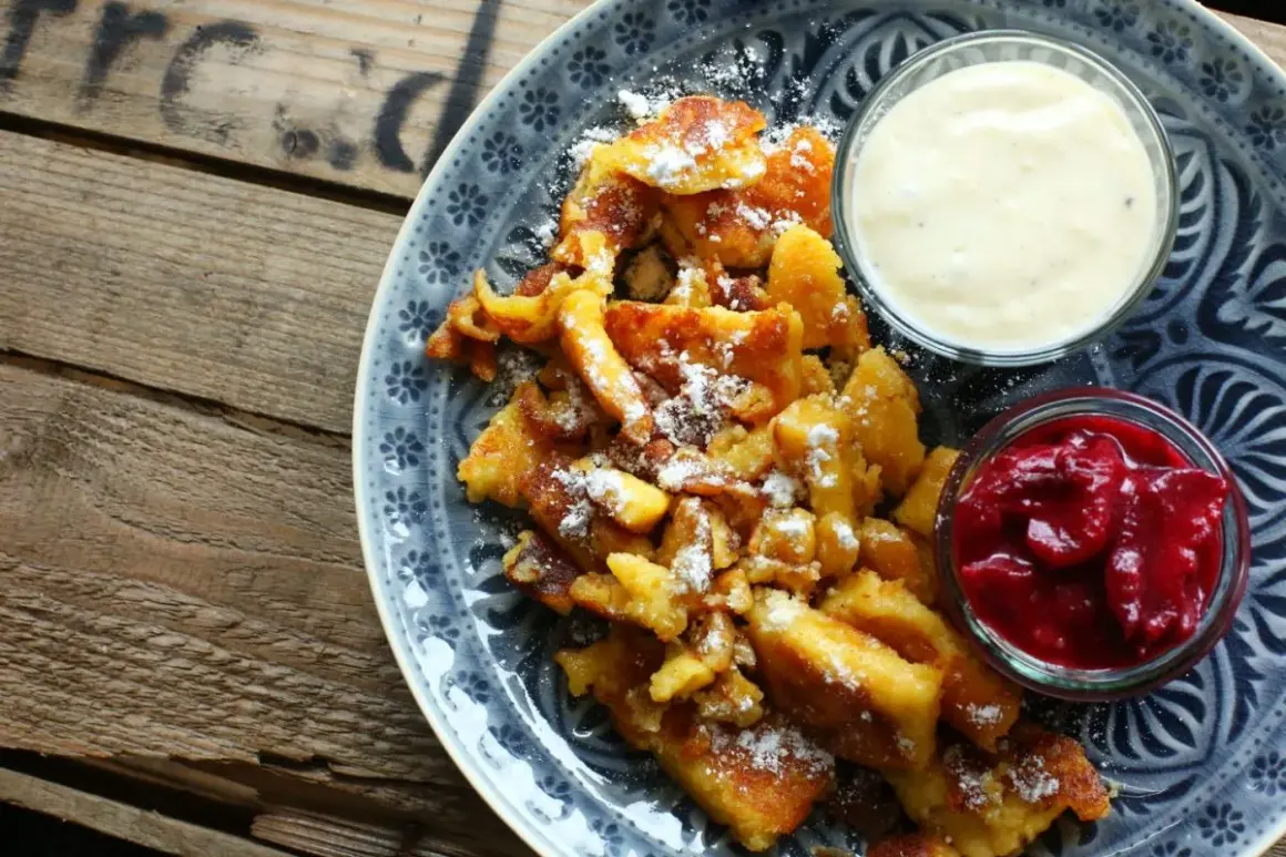 Ein köstlicher Kaiserschmarrn, bestäubt mit Puderzucker, serviert mit Apfelmus und Vanillesauce. Ein einfaches Rezept für Genuss.