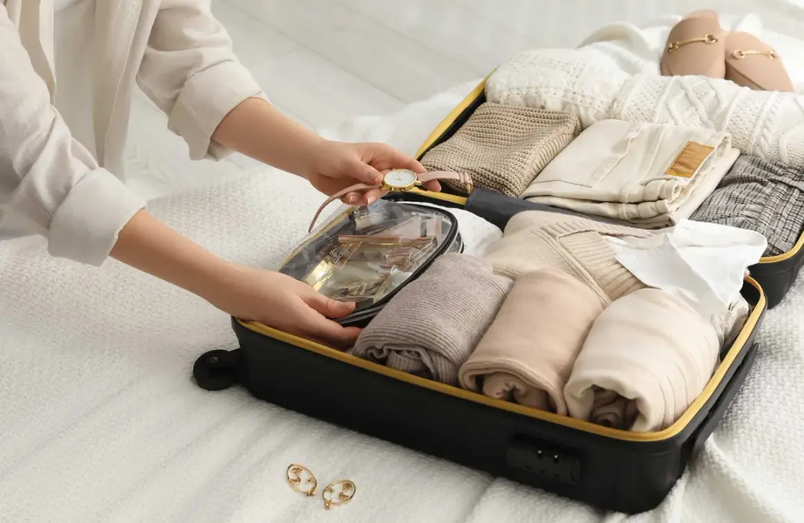 Packa smart för din resa med handbagage. En person organiserar kläder och necessär i en resväska.