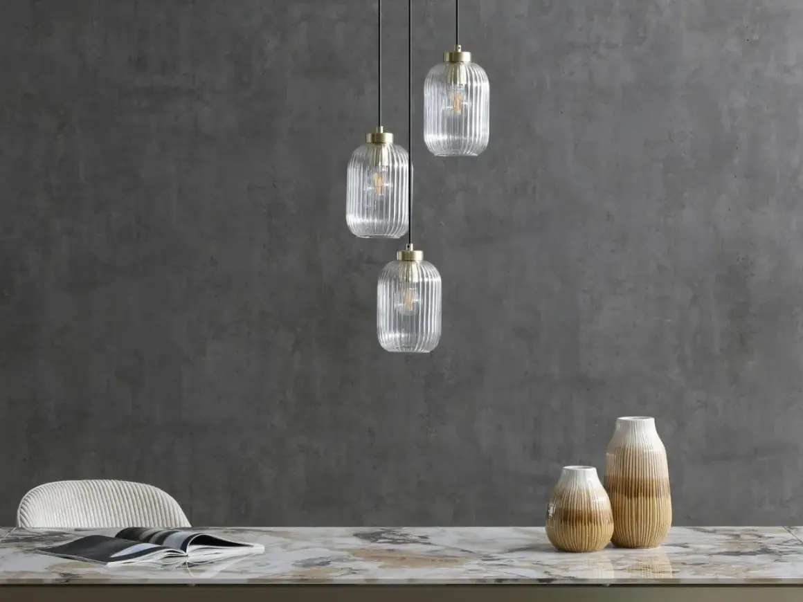 Eleganckie lampy loftowe z przezroczystego szkła wiszą nad marmurowym blatem.