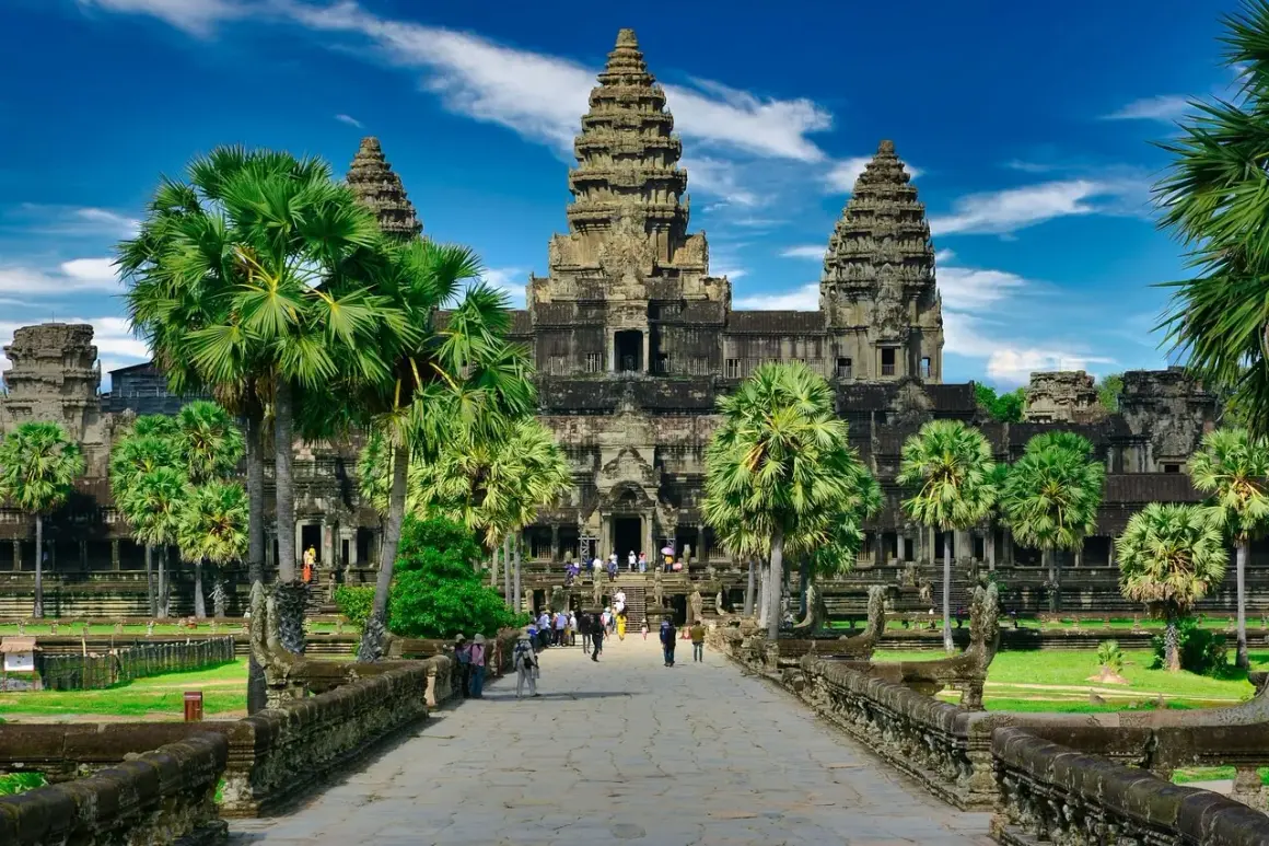 Majestatyczna świątynia Angkor Wat, symbol Kambodży, otoczona palmami pod błękitnym niebem.