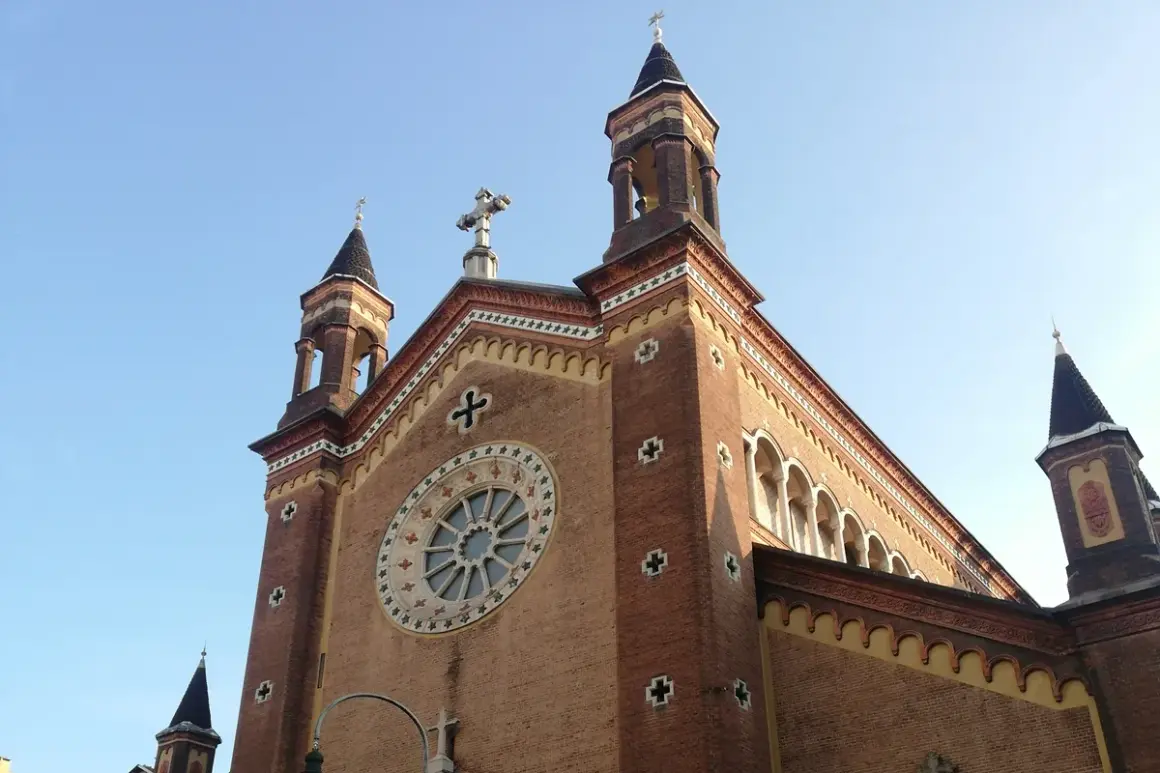 La chiesa San Dalmazzo a Torino, con le sue torri e il rosone, si staglia contro il cielo azzurro.