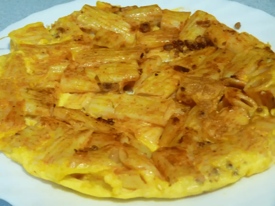 Tortilla de macarrones dorada y apetitosa, con trozos de pasta integrados en el huevo. ¡Un plato casero perfecto!