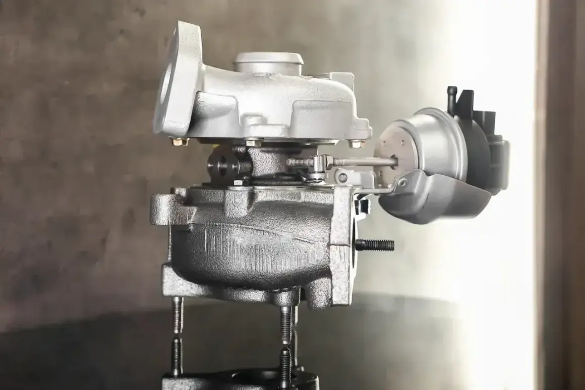 Uszkodzony zawór podciśnienia turbiny objawy: metalowy element turbosprężarki z siłownikiem.