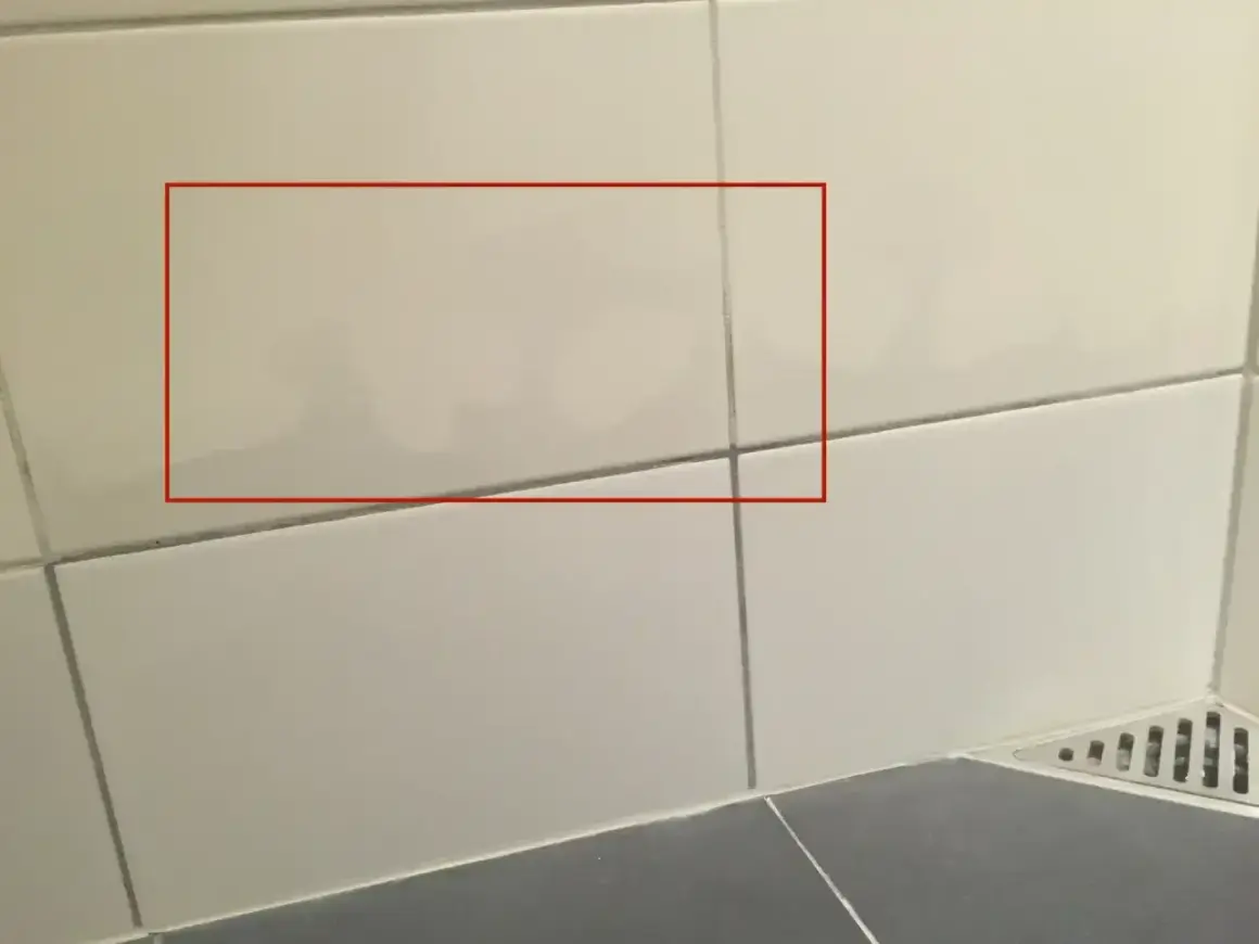 Fuktskada badrum tecken syns som mörka fläckar på kaklet. Vatten har trängt in.