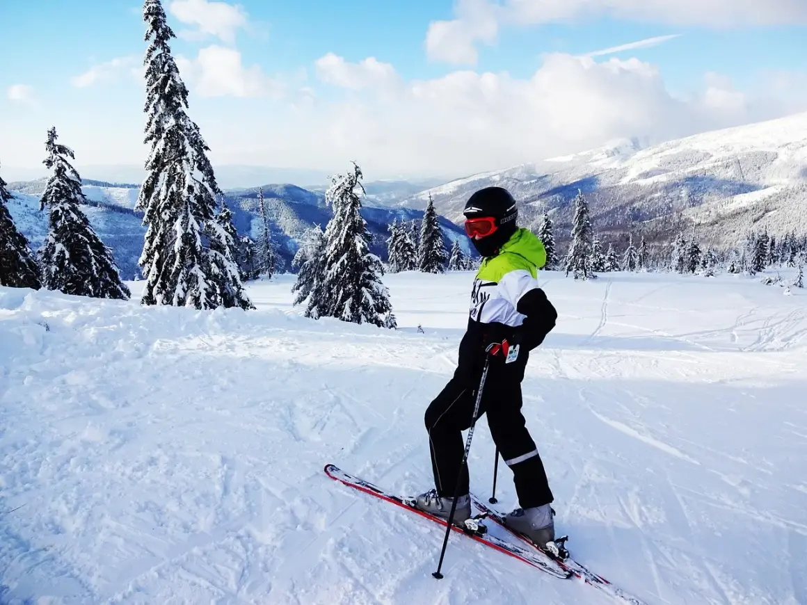 Narciarz na łagodnych stokach narciarskich Zakopane dla początkujących, otoczony ośnieżonymi drzewami i górami.