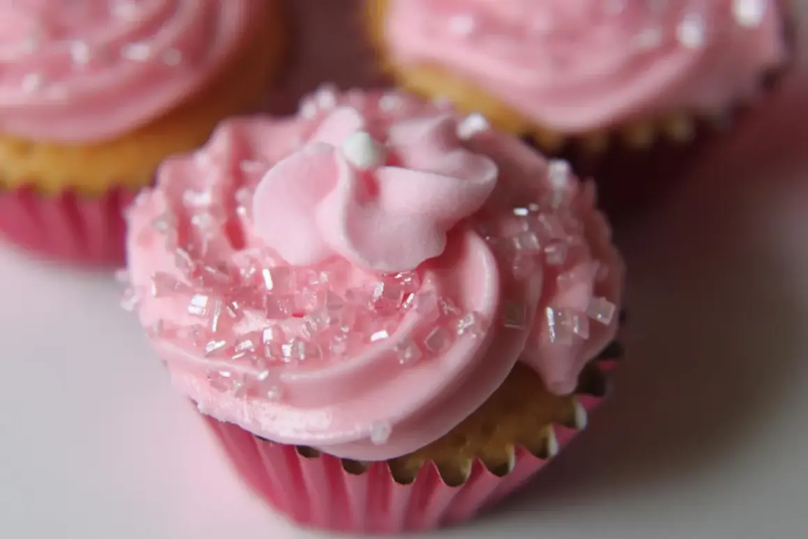 Rosa muffins med sockerströssel och fluffig frosting. Perfekt för en festlig stund.