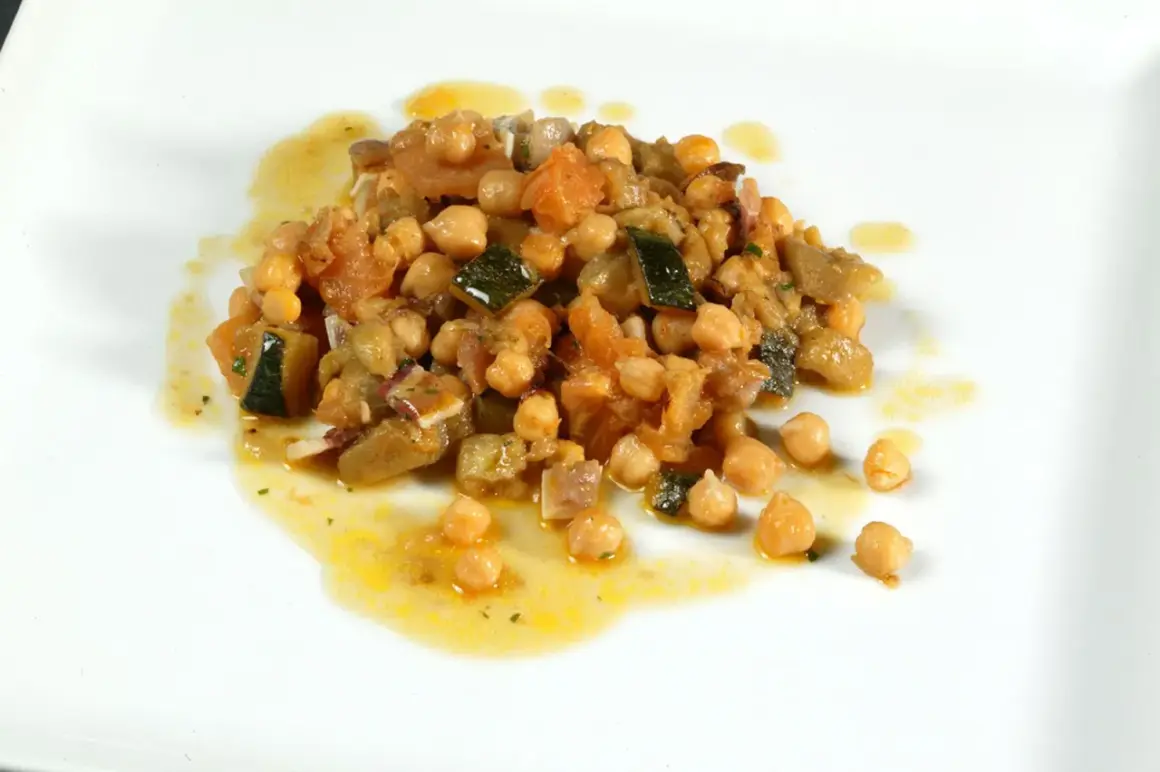 Deliciosos garbanzos con pisto, una mezcla colorida de verduras y legumbres en un plato blanco.
