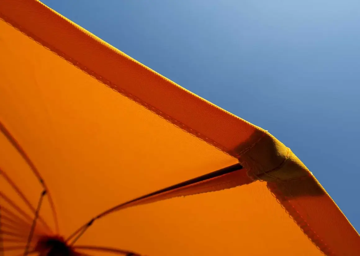 Orange Sonnenschirm-Stoff mit Baumwolle für UV-Schutz vor blauem Himmel.