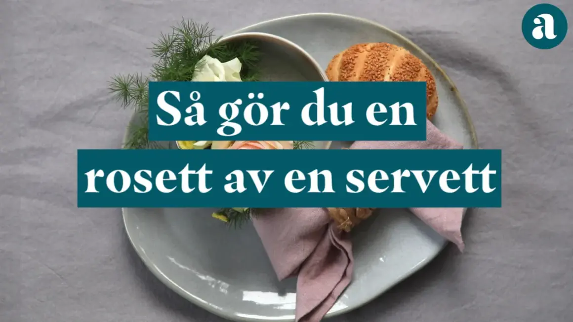 En dukning med en rosett av en servett, blommor och en bulle.