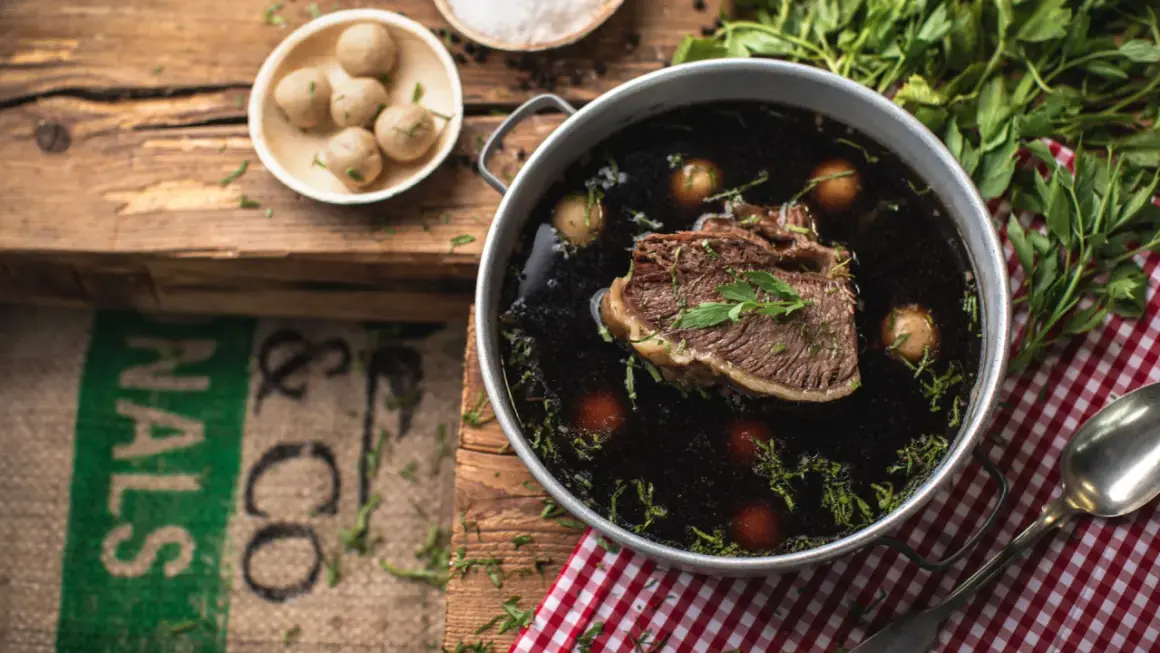 Ein köstliches Tafelspitz-Rezept: Zartes Rindfleisch in dunkler Brühe mit kleinen Klößchen und frischer Petersilie.