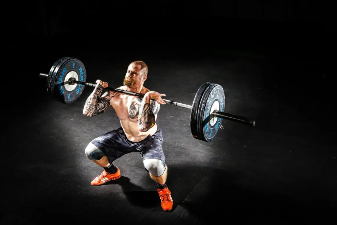 Mężczyzna z tatuażami wykonuje rack pull z ciężarem.
