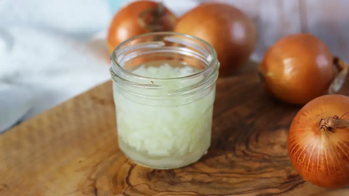 Zwiebelsaft husten: Gehackte Zwiebeln in einem Glas, bereit zur Zubereitung eines natürlichen Heilmittels gegen Husten.