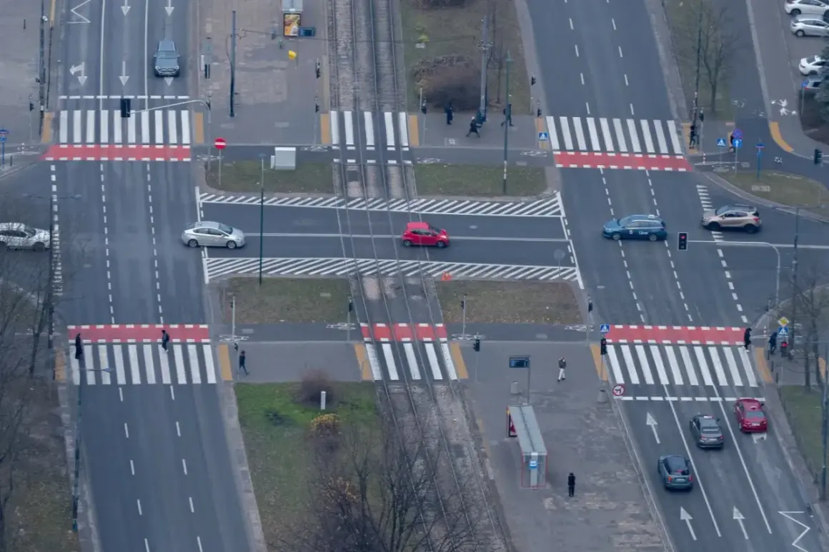 Skrzyżowanie z przejściami dla pieszych. Czerwony samochód jedzie po pasach, zastanawiając się, ile za wyprzedzanie na pasach.