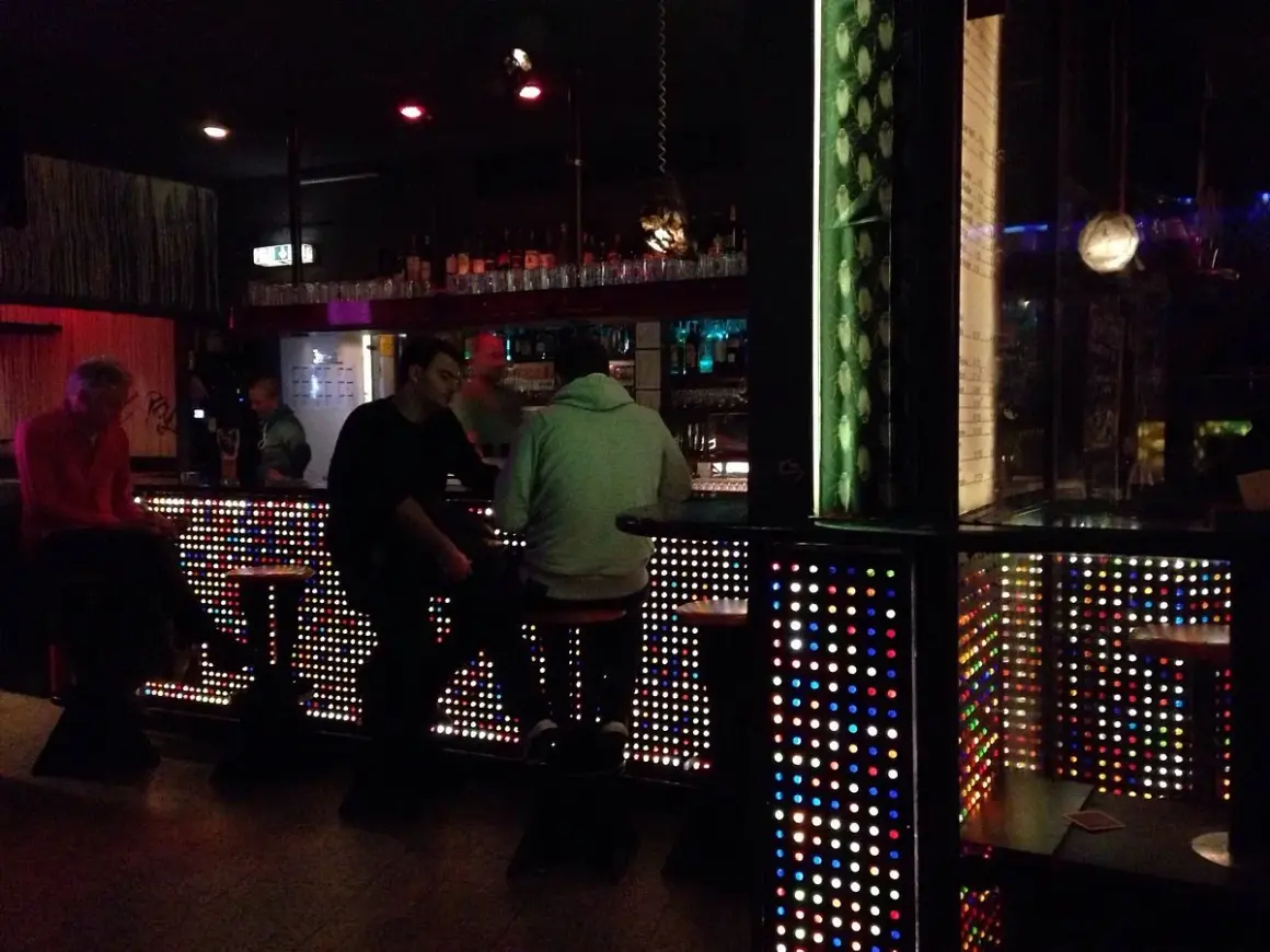 Leute sitzen an einer Bar in Stuttgart, die mit bunten Lichtern beleuchtet ist. Ein gemütlicher Abend im Oblomow.