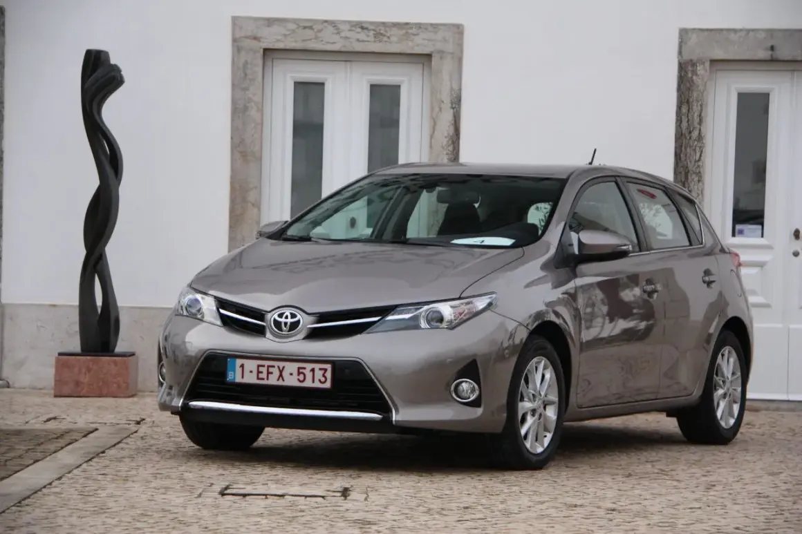 Szary Toyota Auris 1.6 benzyna zaparkowany obok rzeźby.