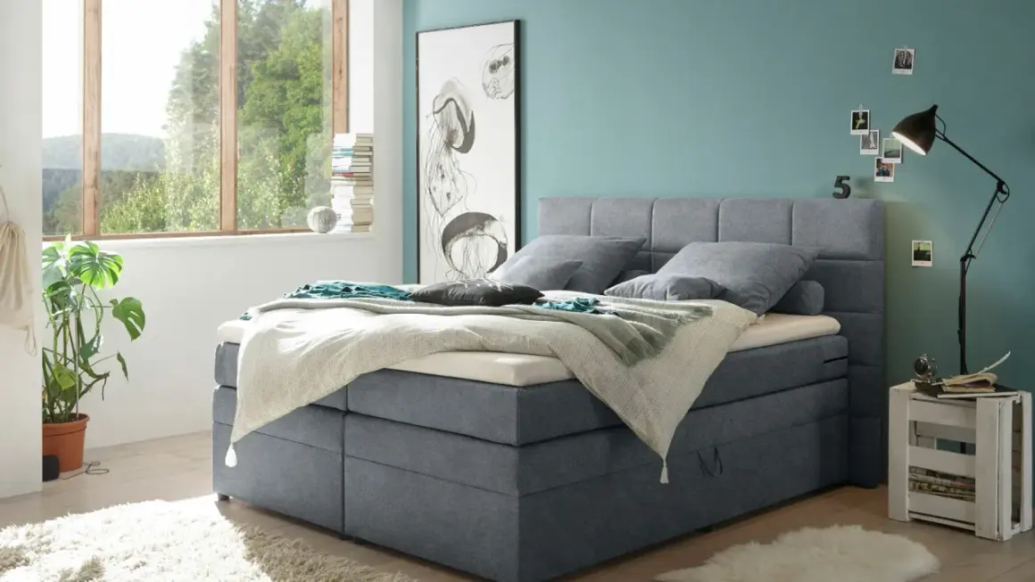 Ein Schlafzimmer mit einem Boxspringbett in Grau und einer Wand in Türkis. Tolle wandfarben ideen für ein maritimes Flair.