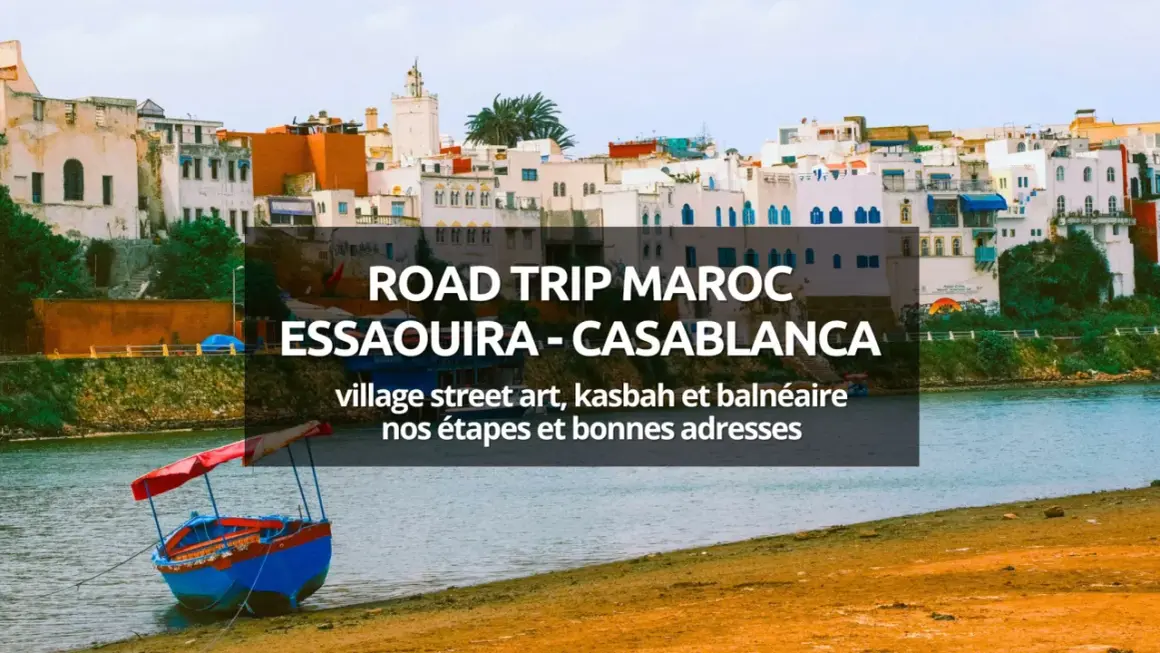 Bateau coloré sur la rive d'une ville côtière marocaine, avec des bâtiments blancs et bleus en arrière-plan.