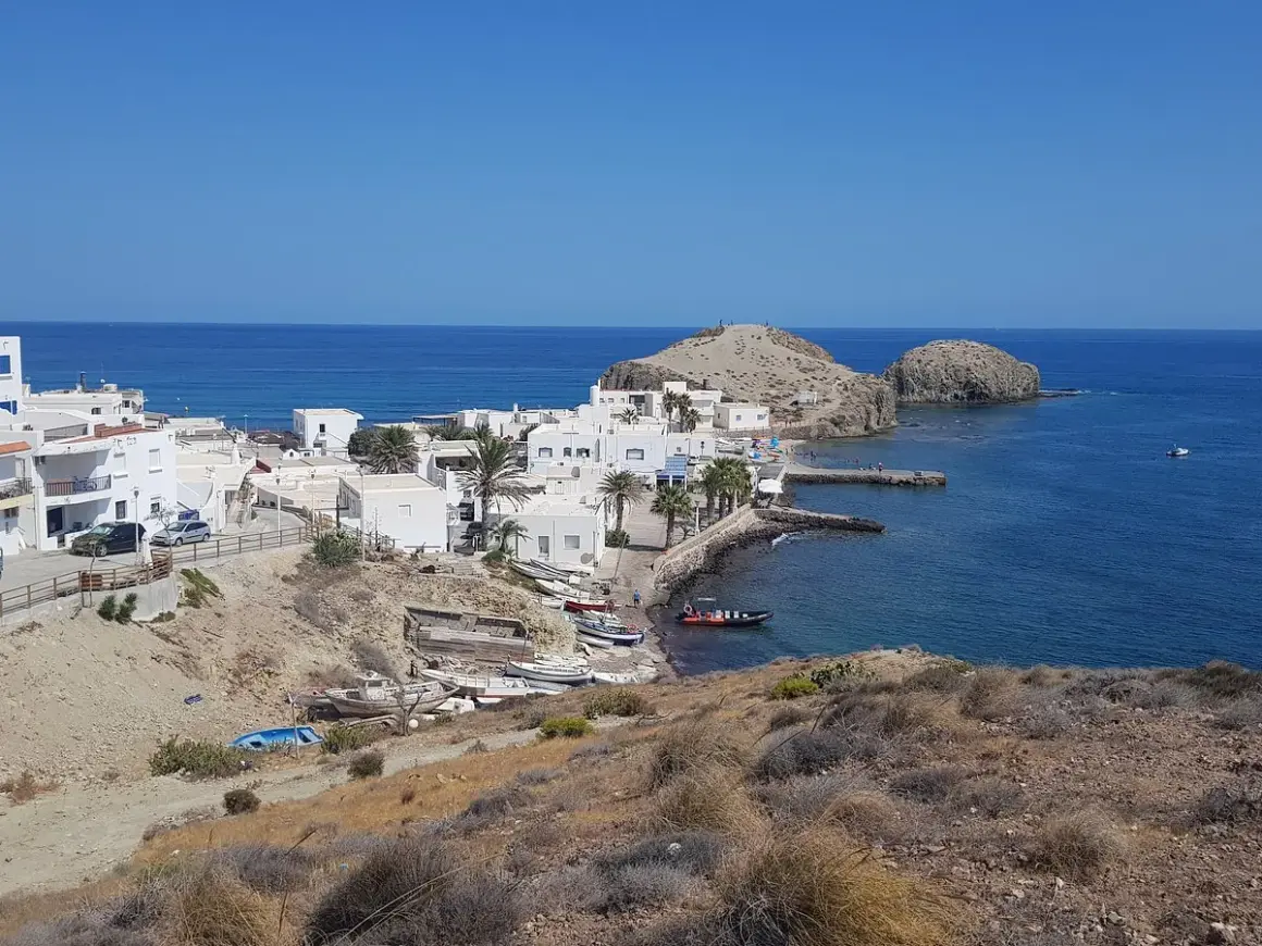 Vista panorámica de la **isleta del Moro, Almería**, con casas blancas, barcas y el mar azul.