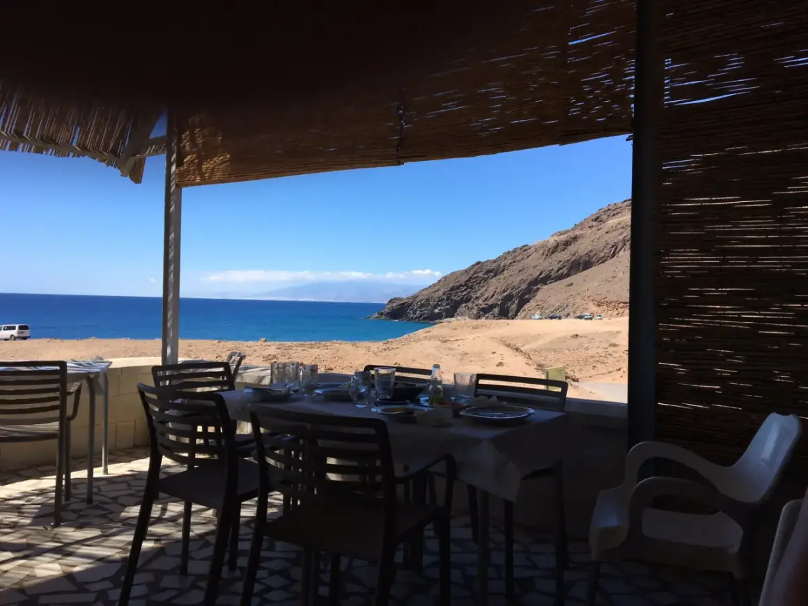 Mesas puestas en restaurantes en La Fabriquilla, Cabo de Gata, con vistas al mar y a la montaña.