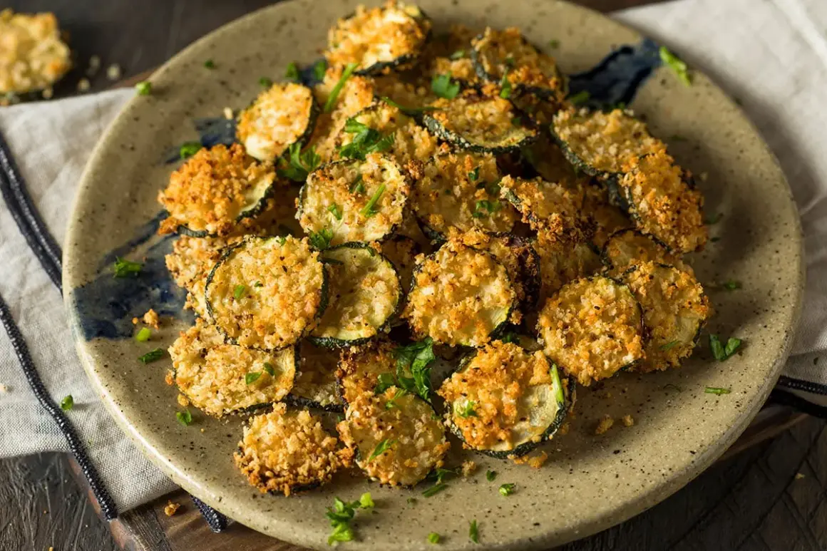 Fette croccanti di zucchine in friggitrice ad aria con pangrattato dorato, guarnite con prezzemolo fresco.