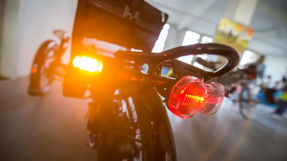 Blinker am Fahrrad leuchten orange und rot. Das Rücklicht ist klar erkennbar, während das vordere Licht diffus strahlt.