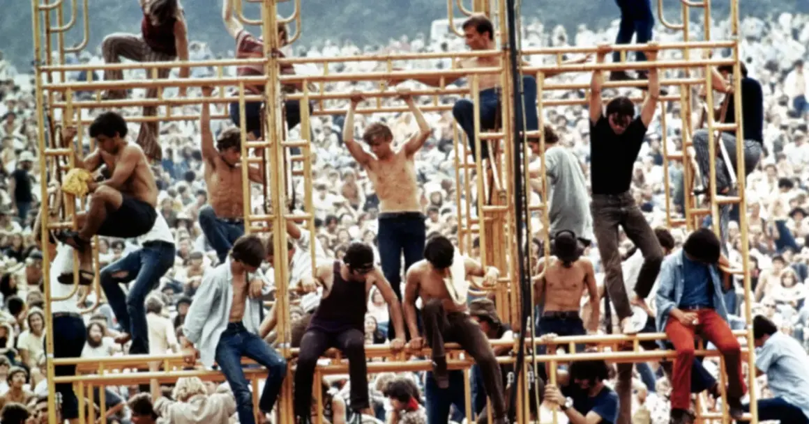 Ludzie wspinający się na żółtą konstrukcję podczas festiwalu Woodstock 1969.