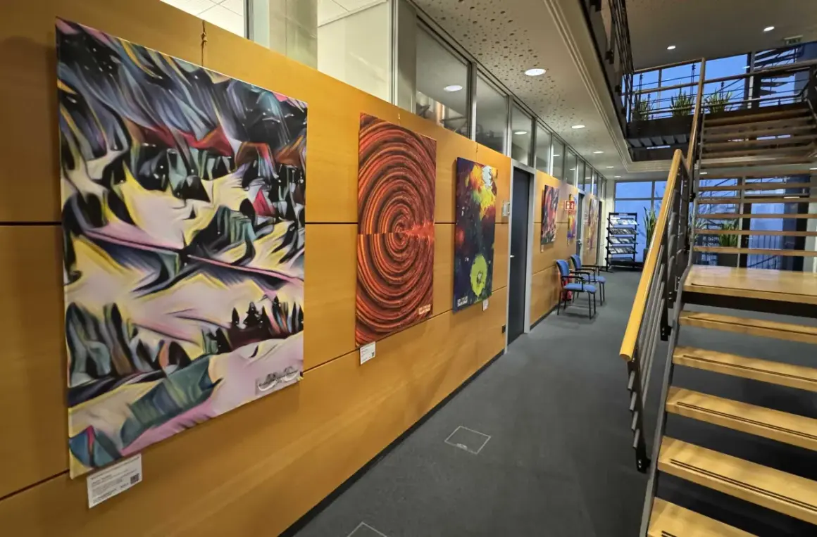 Moderne Kunstwerke schmücken die Wand einer Galerie in Bergisch Gladbach. Eine Treppe führt nach oben.