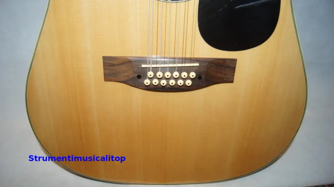 Chitarra acustica a 12 corde con ponte in legno scuro e materiale corde chitarra acustica in primo piano.