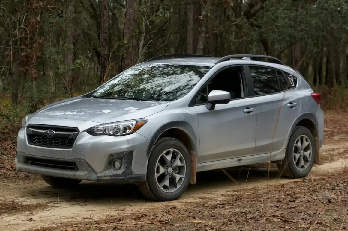 Srebrny Subaru Crosstrek na leśnej drodze, gotowy na przygodę.