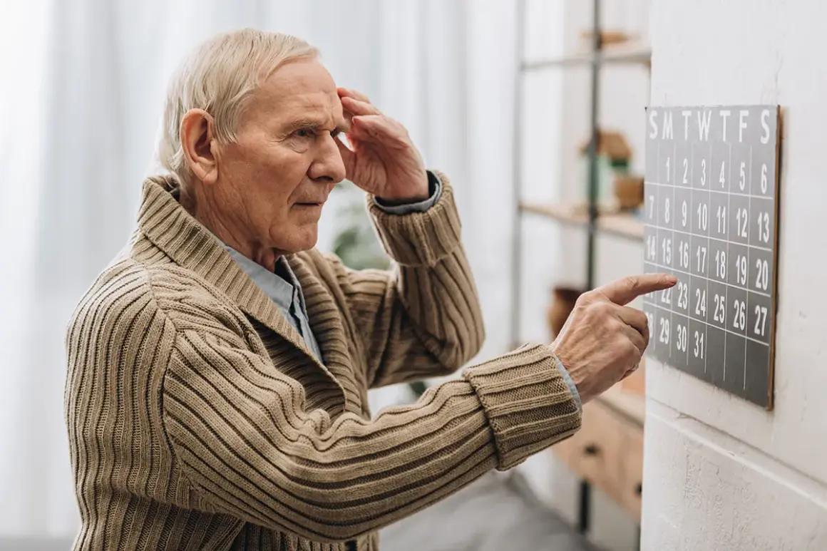 Älterer Mann mit Hand an der Stirn blickt auf Kalender. Ein Zeichen für Vergesslichkeit im Alter, wenn Daten verschwimmen.