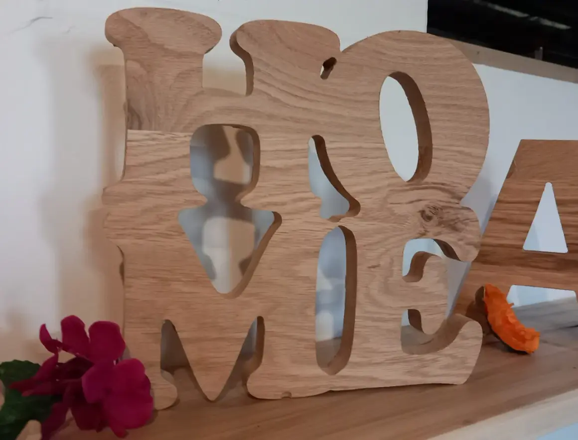 Grosse lettre en bois formant le mot "HOME", décorée de fleurs et d'une petite décoration orange.