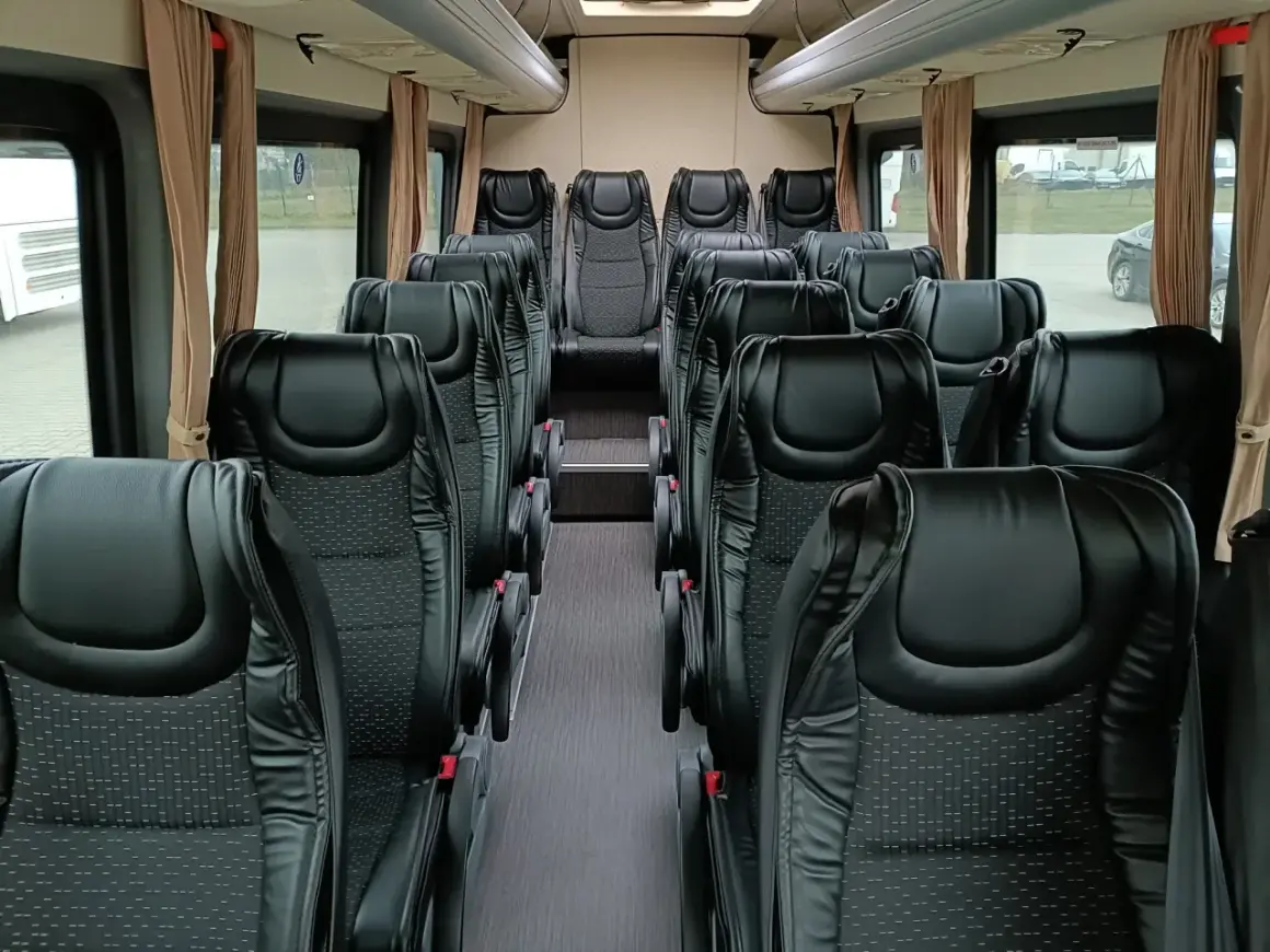 Wnętrze busa 20 osobowego z rzędami czarnych, wygodnych foteli. Idealny na wycieczki i transport grupowy.