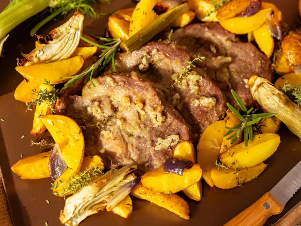 Saftiges Schweinesteak im Backofen ohne Anbraten, umgeben von goldbraunen Kartoffelspalten, Fenchel und Kräutern.