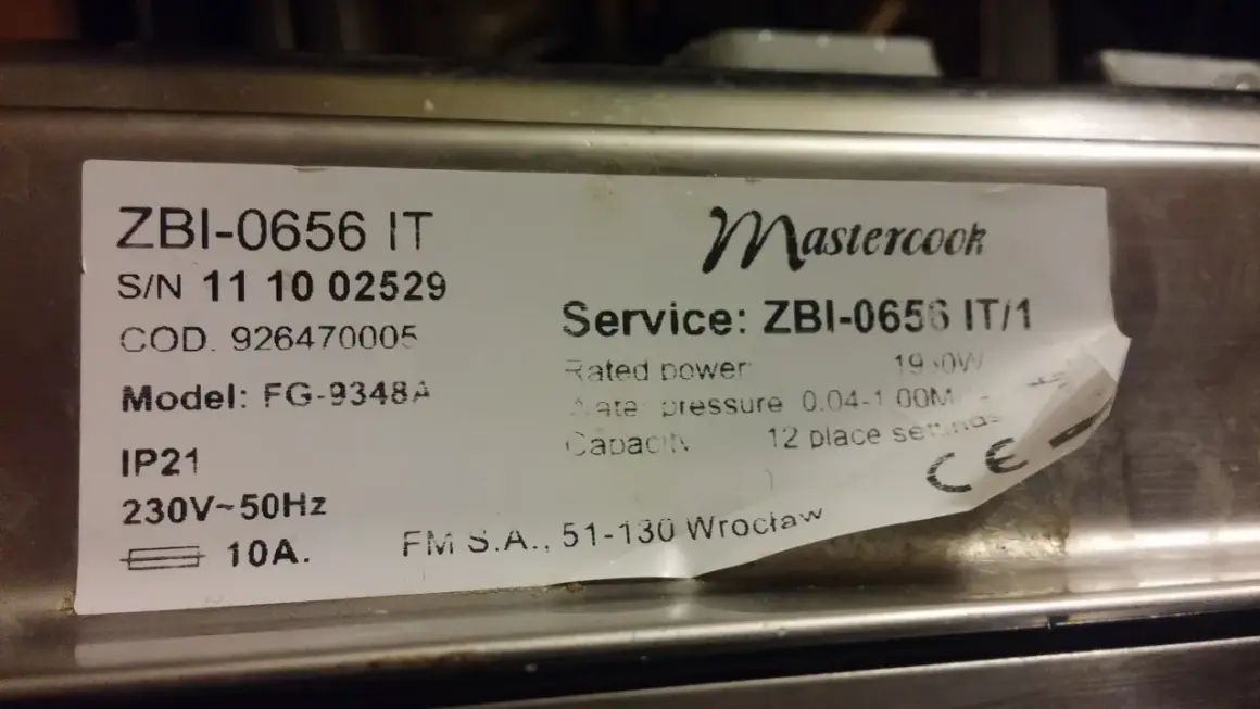 Naklejka z danymi technicznymi kuchenki Mastercook ZBI-0656 IT. Znajdziesz tu m.in. numer seryjny, model FG-9348A, moc 1950W, ciśnienie wody 0.04-1.00M, pojemność 12 kompletów.