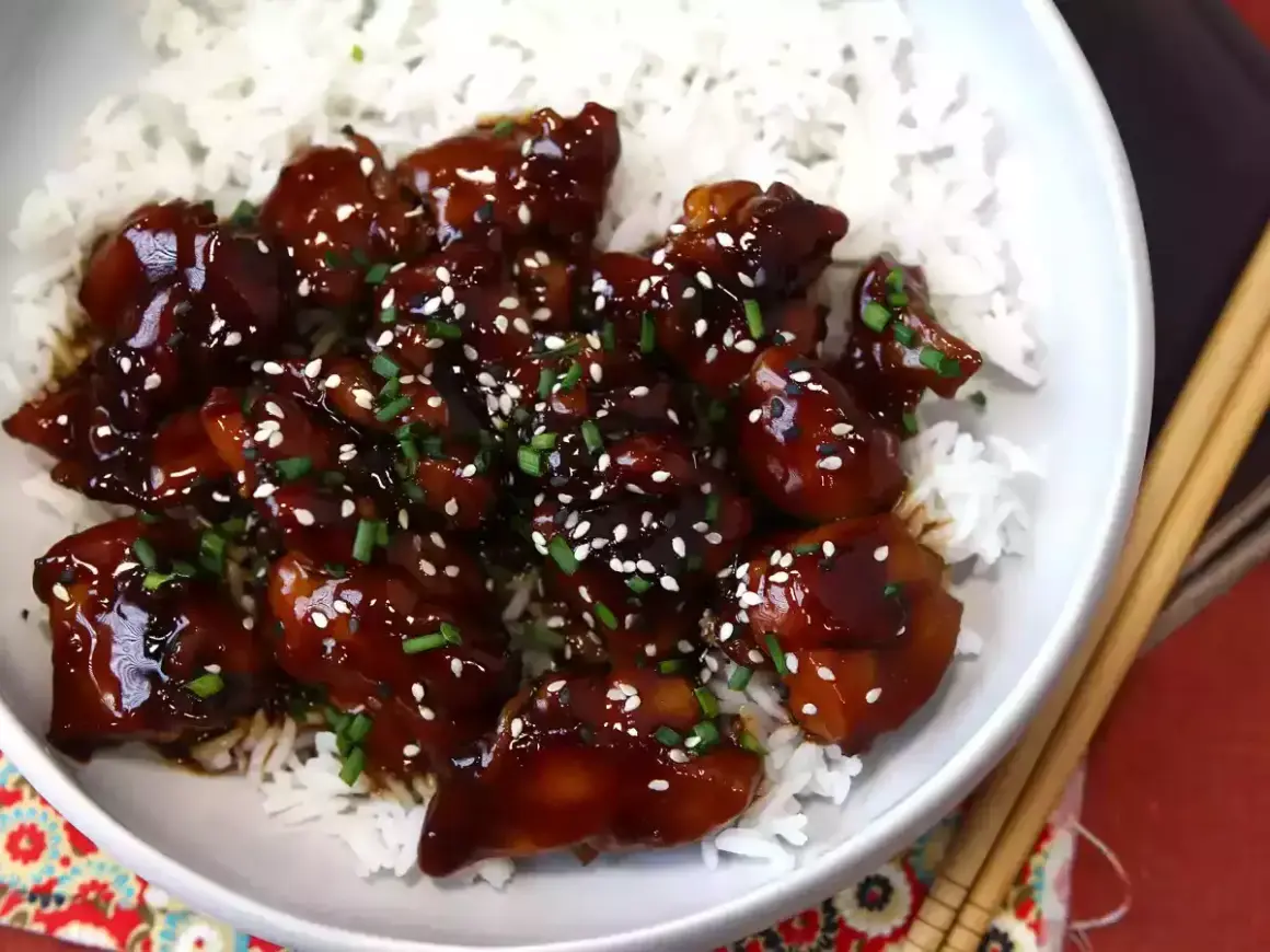 Kyckling i glansig teriyakisås med sesamfrön och gräslök, serverad över ris. Ett enkelt teriyakisås recept att prova.