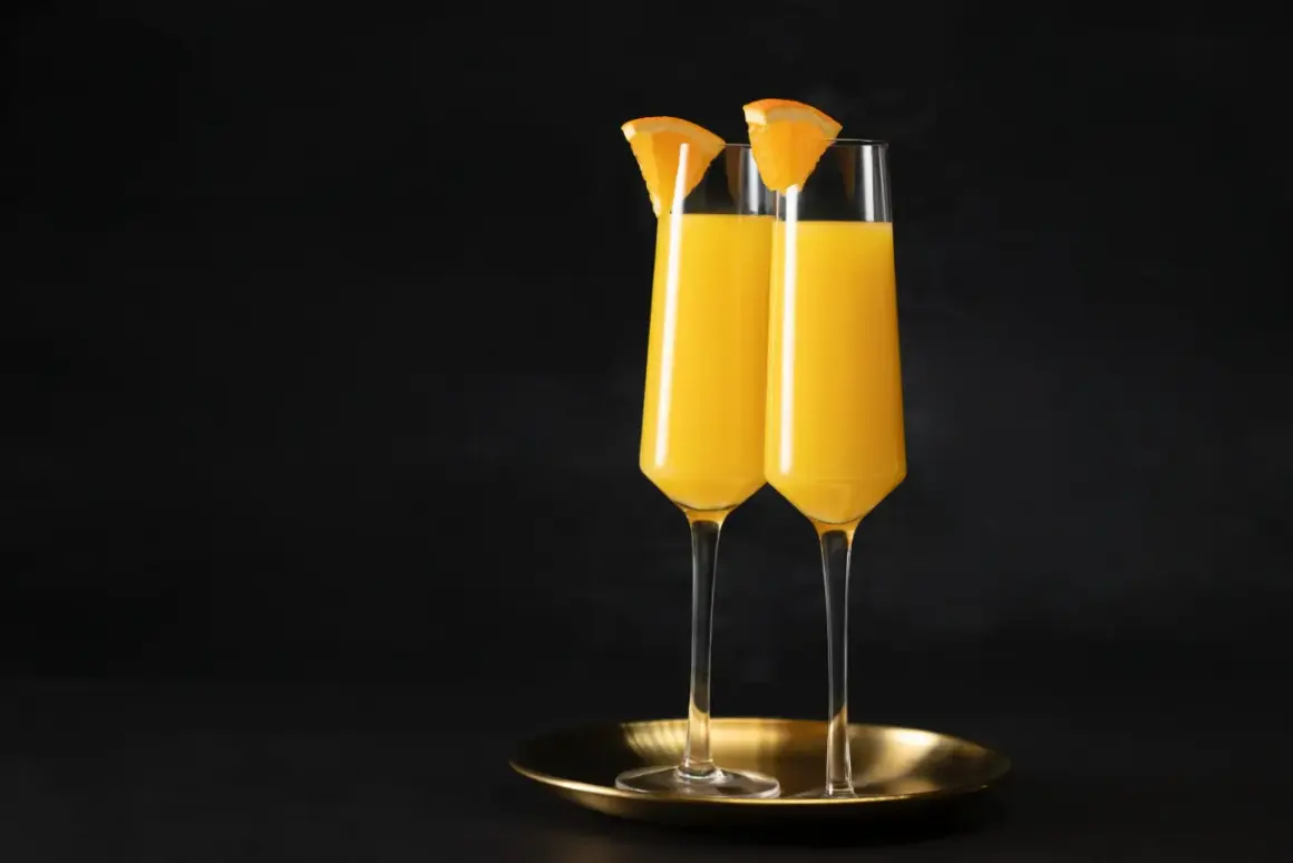 Dwa kieliszki wypełnione złocistym płynem, ozdobione plasterkami pomarańczy. Idealny duet na brunch, klasyczny mimosa.