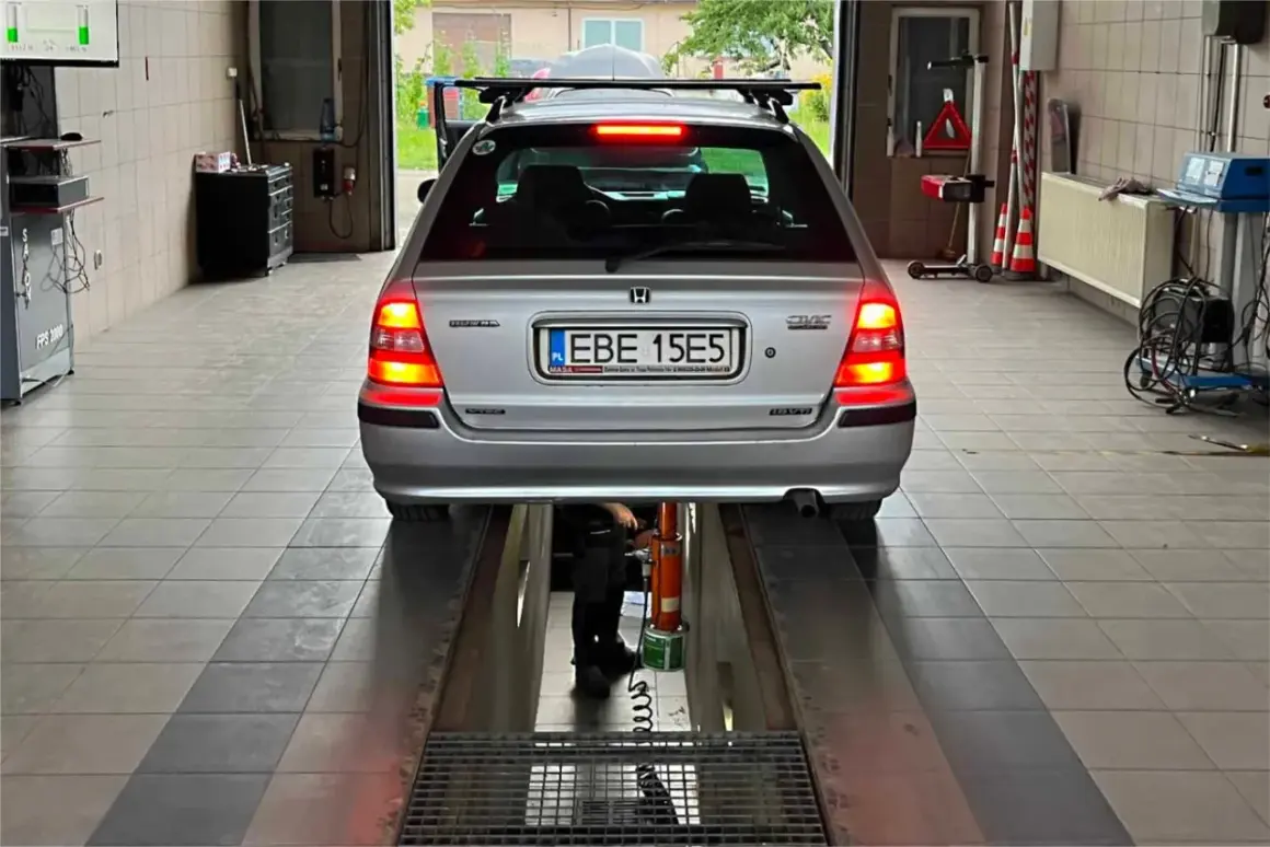 Srebrny Honda Civic na podnośniku w warsztacie. Tablica rejestracyjna EBE 15E5. Może poprzedni właściciel nie przerejestrował auta?