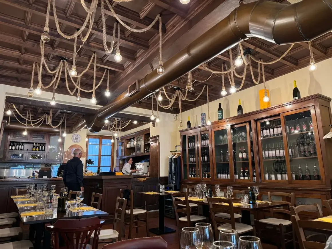 Interno di un ristorante con tavoli apparecchiati e una grande vetrina di vini. Un locale che potrebbe essere tra i migliori ristoranti di Milano per l'atmosfera.