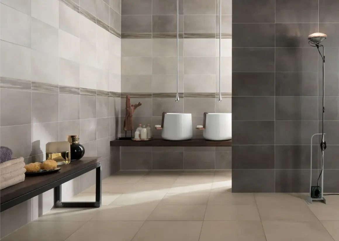 Bagno moderno con lavabi sospesi e piastrelle a diverse altezze, che creano un effetto visivo dinamico.