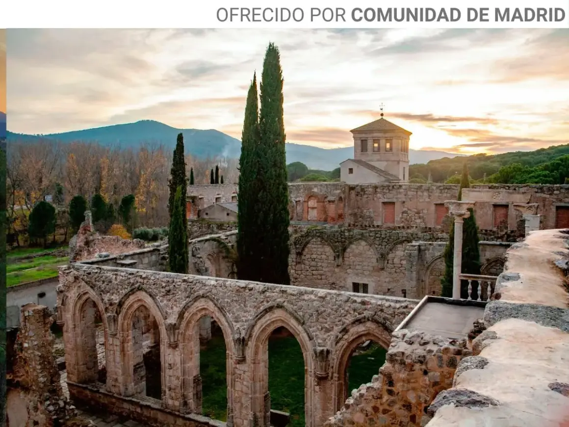 Ruinas de antiguos monasterios cerca de Madrid, con arcos de piedra y cipreses altos bajo un cielo crepuscular.