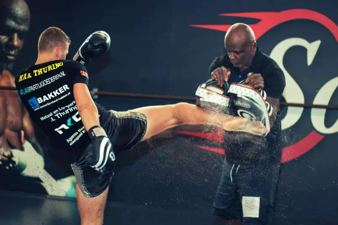 En fighter sparkar mot en träningspad som hålls av en tränare. Kanske en träning med Ernesto Hoost?