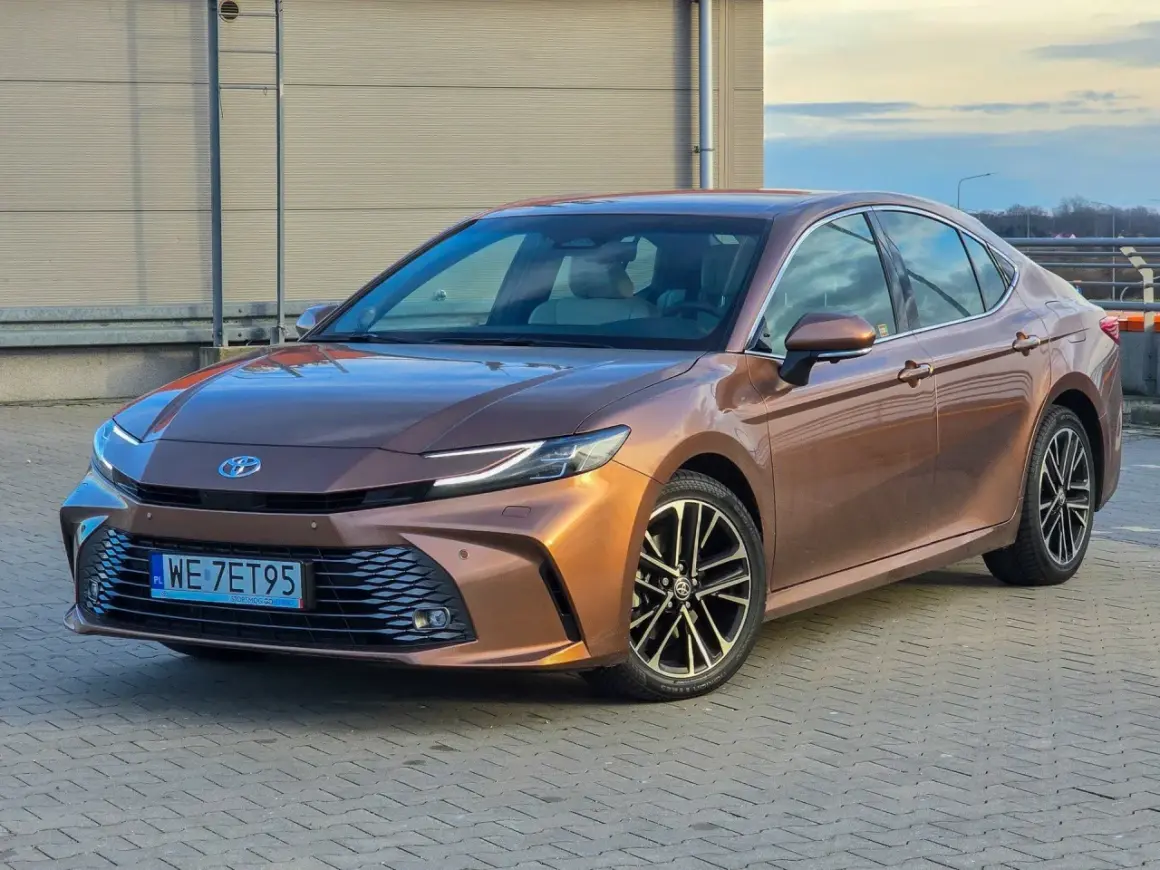 Brązowa Toyota Camry 2.5 Hybrid prezentuje się elegancko, a jej niskie spalanie to atut dla kierowców.