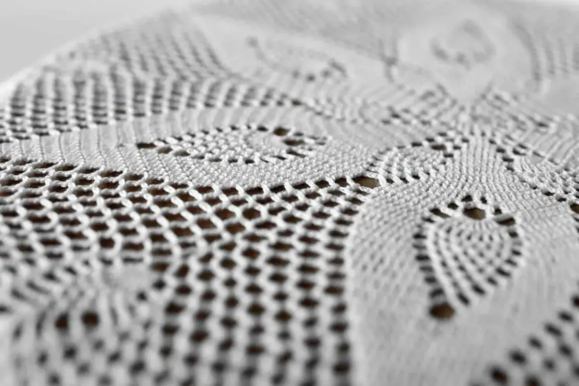 Dettaglio di un centrino all'uncinetto bianco, con motivi floreali e traforati. Un tocco di eleganza che dimostra come si usano ancora i centrini sui mobili.