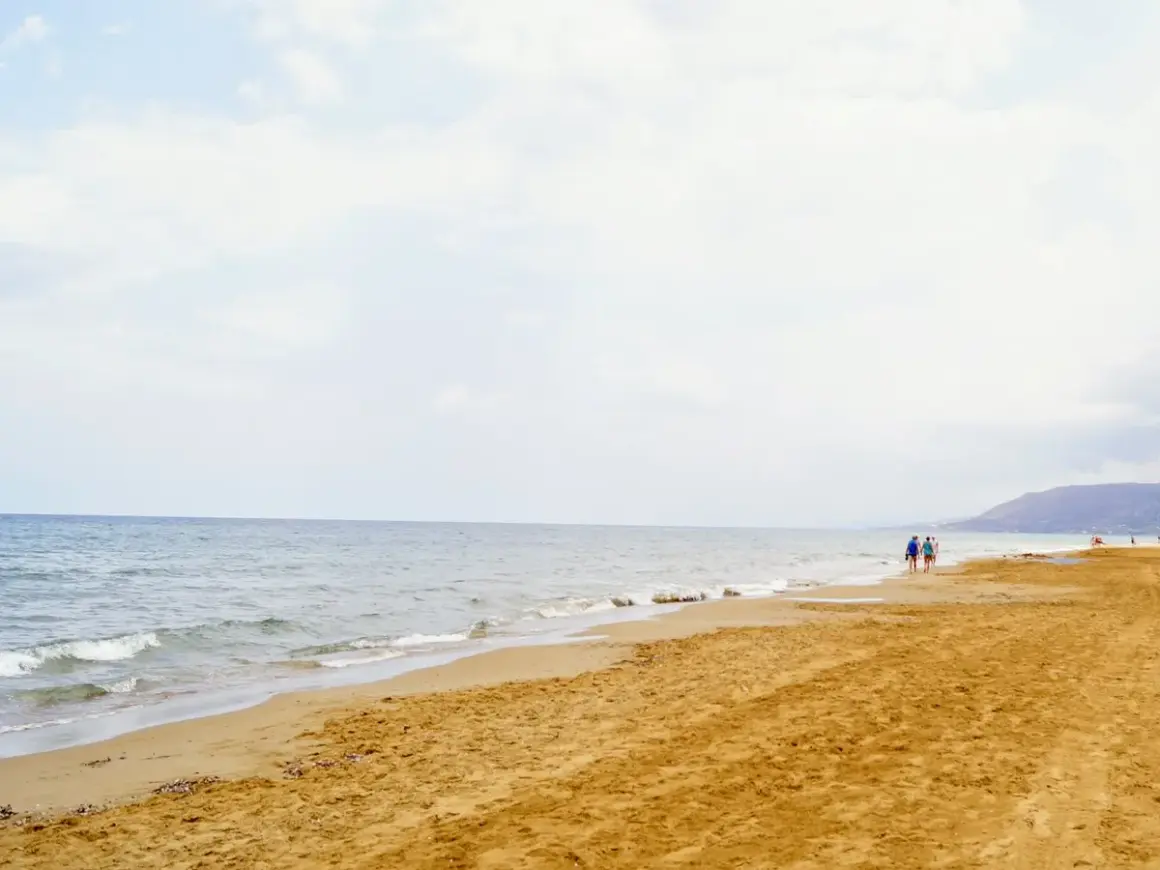 Spokojne morze i piaszczysta plaża na Zakynthos w maju. Kilka osób spaceruje brzegiem, ciesząc się łagodnym słońcem i ciszą.
