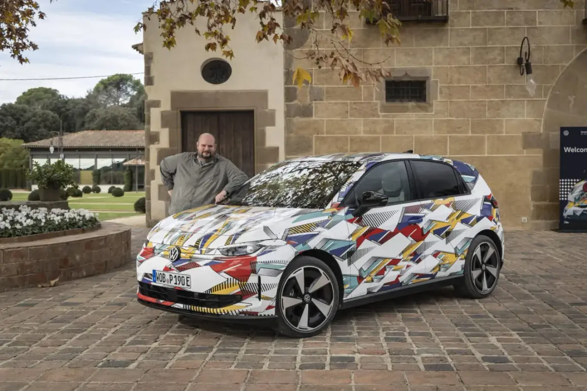 Man lutar sig mot en Volkswagen ID.2 med ett färgglatt, geometriskt mönster.