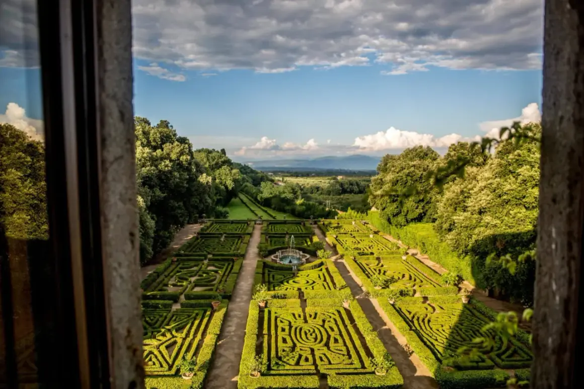 Giardini all'italiana del Castello Ruspoli, con siepi geometriche, fontana centrale e vista panoramica sulla campagna.