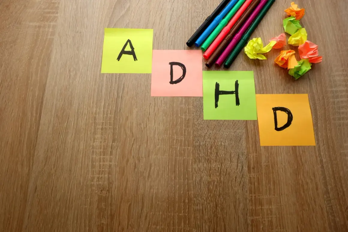 Kolorowe karteczki z literami A, D, H, D układają się w napis ADHD. Obok leżą flamastry i pomięte kartki.